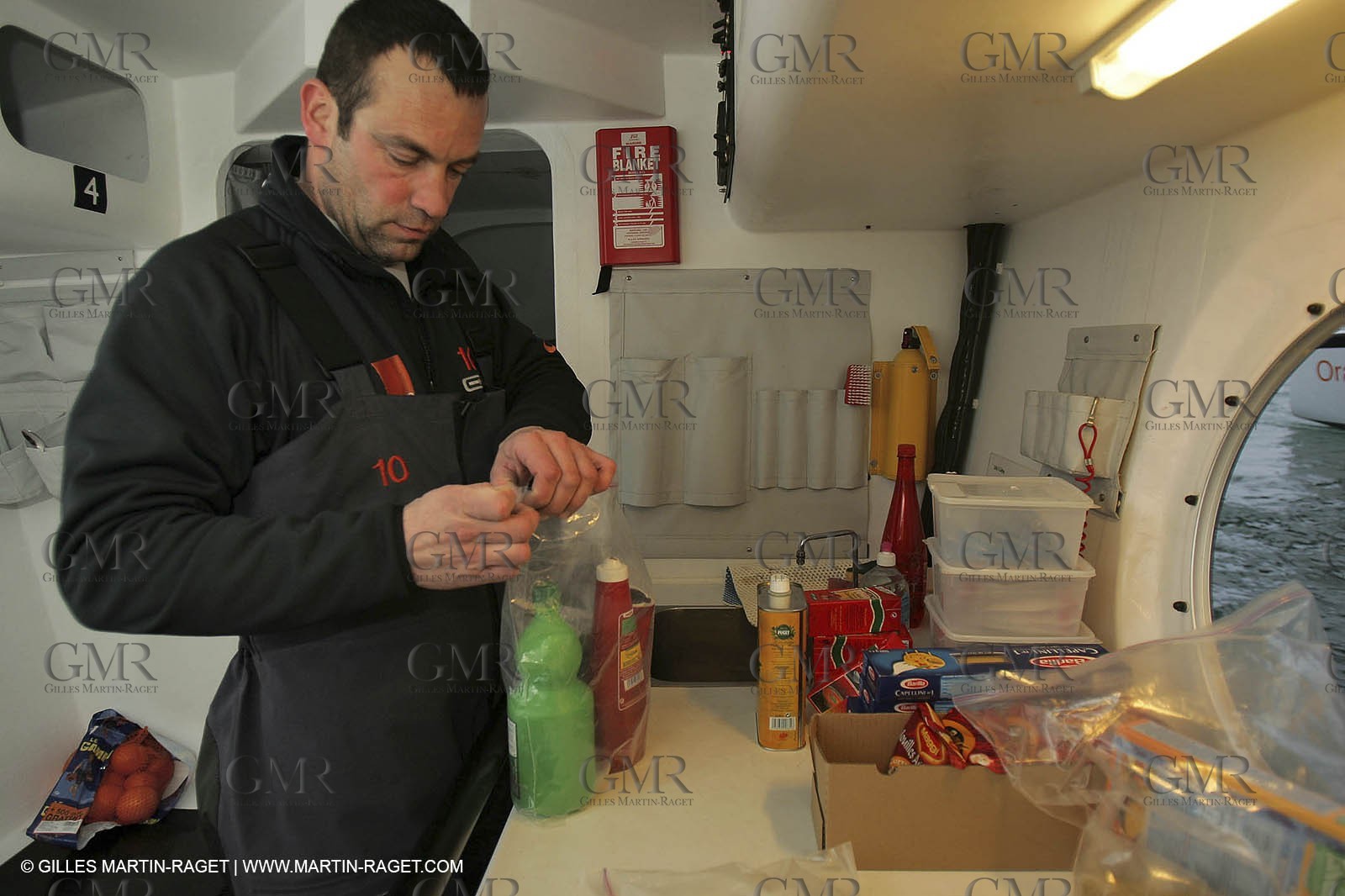 Orange II - Jules Verne Trophy 2004 - Jean-Baptiste Epron preparing food in the galley